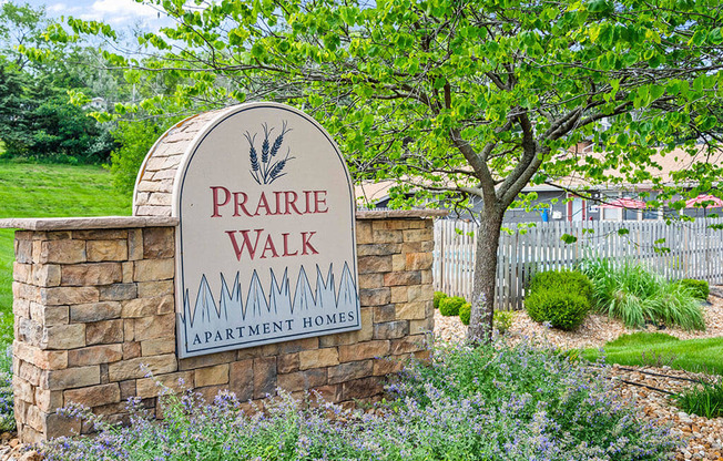 a sign for prairie walk apartments in front of a tree