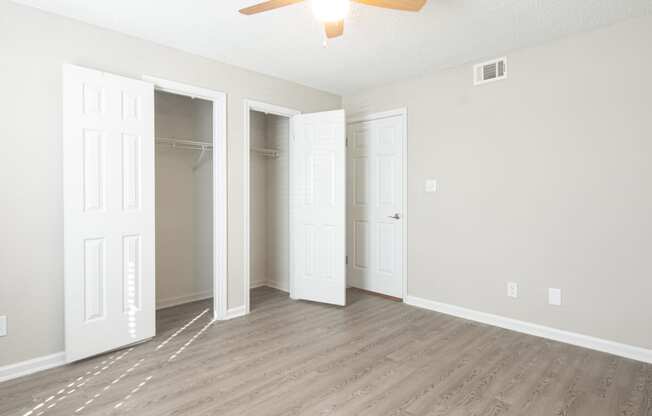 an empty living room with three closets and a ceiling fan