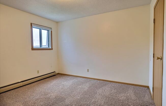 Bedroom with carpeted floors and a window at Parkwest Gardens West Fargo