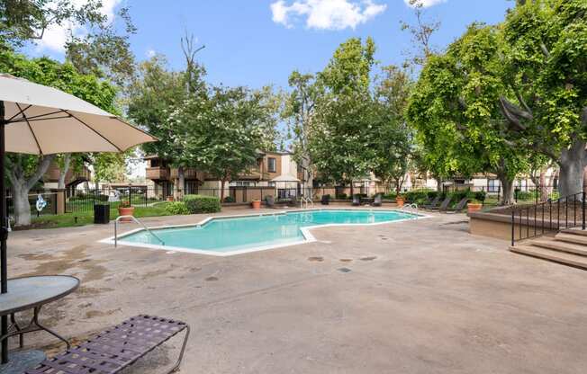 a swimming pool with trees and umbrellas at the enclave at woodbury apartments