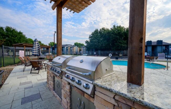 an outdoor kitchen with a grill next to a pool