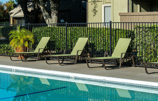 two lawn chairs sitting next to a swimming pool