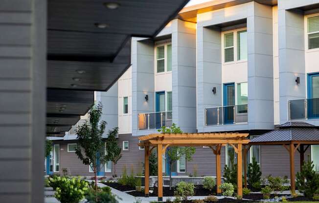 A modern building with a balcony and a wooden pergola in front.