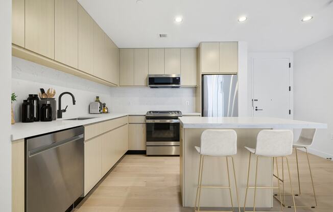a kitchen with white cabinets and a island with three stools at The Paxton, Brooklyn, NY 11201