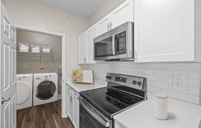 a kitchen with white cabinets and black appliances and a white washer and dryer