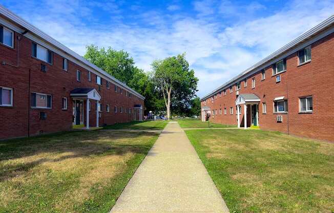 A long pathway leads between two rows of red brick buildings.