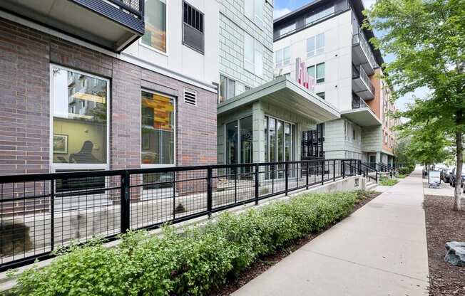 a sidewalk in front of a building with a black fence