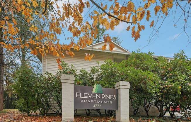 A sign for Eleven Pines Apartments stands in front of a building.