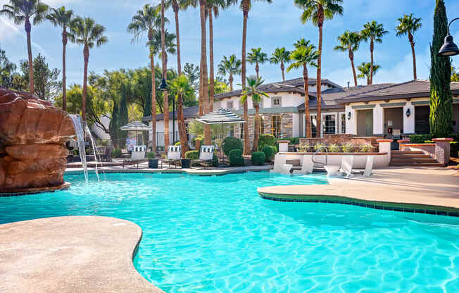 Spring Valley Apartments - Alicante - Pool with White Lounge Chairs, Palm Trees, Umbrella Tables, and View of Sundeck