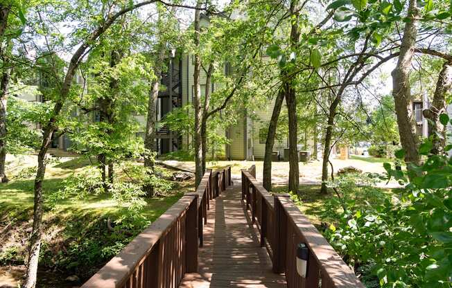 a wooden bridge in the middle of a park with trees