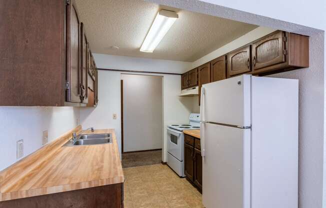 an empty kitchen with a refrigerator and a sink. Fargo, ND Plumtree Apartments