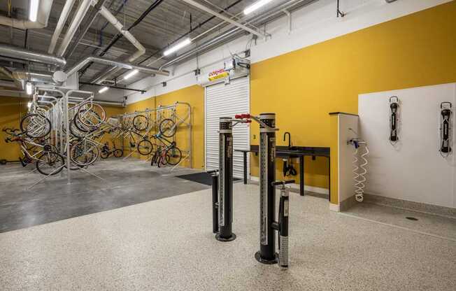 A bike repair shop with a yellow wall and bicycles hanging from the ceiling.