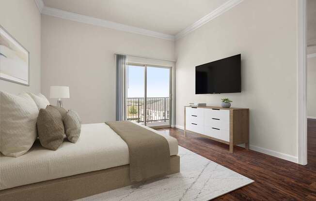 A bedroom with a large bed, a flat screen TV, and a window with a view of a balcony.