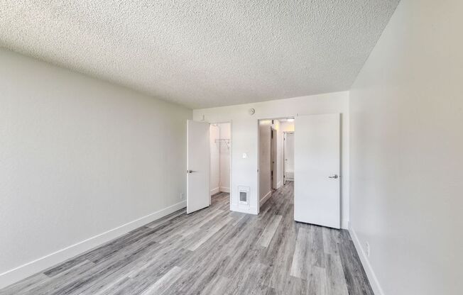 a bedroom with hardwood floors and white walls