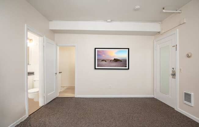 a living room with a painting on the wall and a door to a bathroom