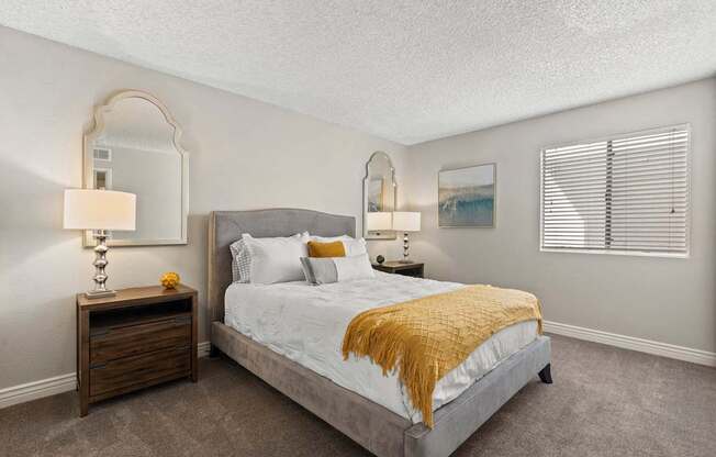 A bedroom with a bed, nightstand, and two wall lamps.