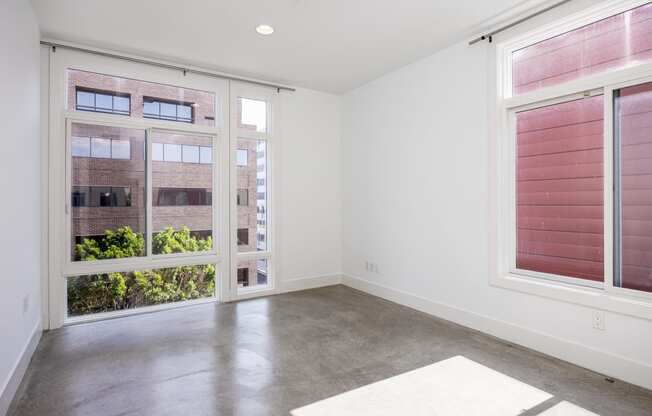 an empty living room with large windows and a concrete floor