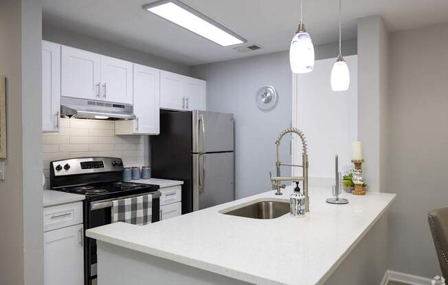 A kitchen with a black refrigerator and white cabinets.