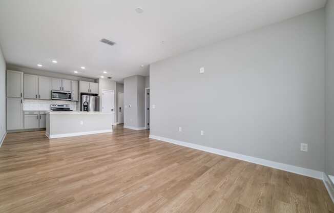 a living room and kitchen with wood floors and white walls