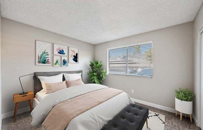 A bedroom with a large bed and a plant on the windowsill.