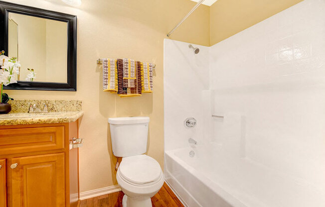 A white toilet sits next to a white bathtub in a bathroom.