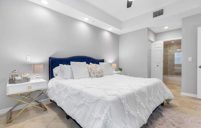 A bedroom with a white bed and a white nightstand.