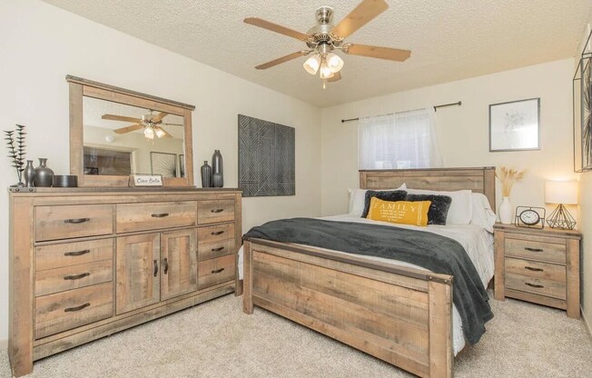 Step into the inviting charm of The Riley Apartments. This beautifully designed bedroom features natural wood accents, ample storage, and cozy ambiance, perfect for relaxation after a long day. Check out what your new home could look like!