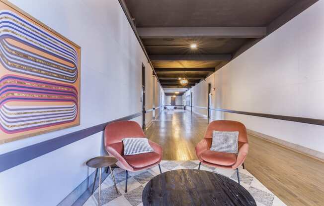 a hallway with two chairs and a table and a painting on the wall