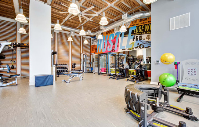 a gym with weights and cardio machines and a large wall with a sign on it