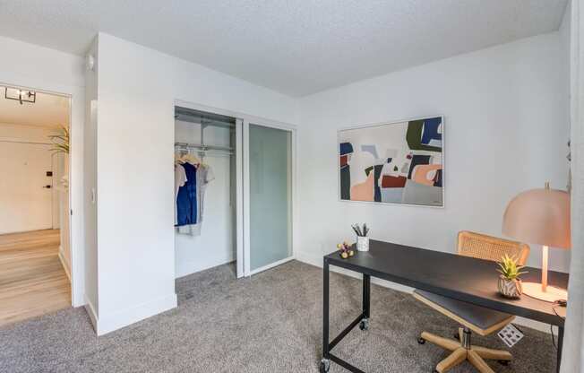 Fusion Warner Center two bedroom apartment in Woodland Hills carpeted office with minimalist desk, closet, and modern painting on wall.