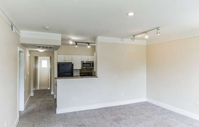 a renovated living room and kitchen with white walls and a carpet floor
