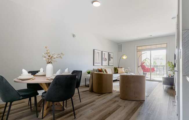 a living and dining area with a wooden floor and a sliding glass door leading to a balcony at Bristol Station Apartments, Carteret, New Jersey