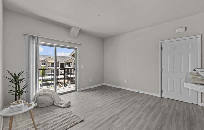 A room with a white door, a table with a plant, and a window with a view of a building outside.