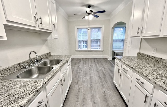 A kitchen with white cabinets and a marble countertop.