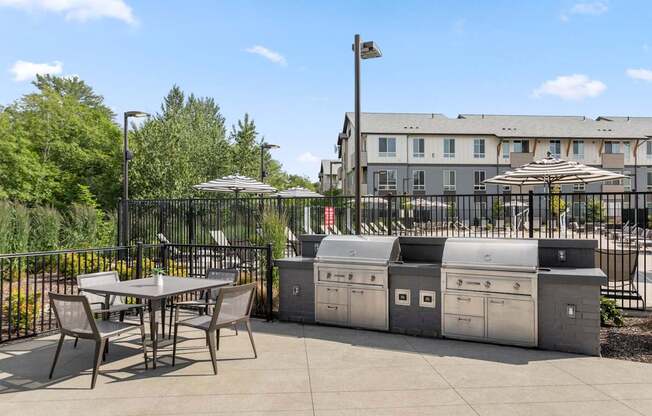 A patio with a table, chairs, and a trash can.
