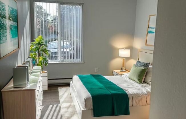 A bedroom with a bed, nightstand, and window.