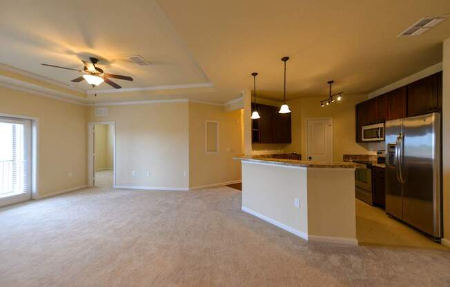 Kitchen and living room with white appliances and brown cabinets.