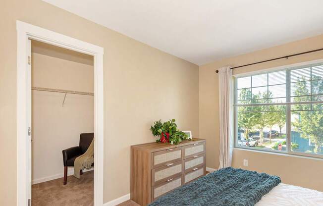 A bedroom with a bed, chair, and window at The Landing Apartments and Townhomes, Oregon, 97045