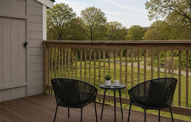 Two black chairs are on a wooden deck with a table between them.
