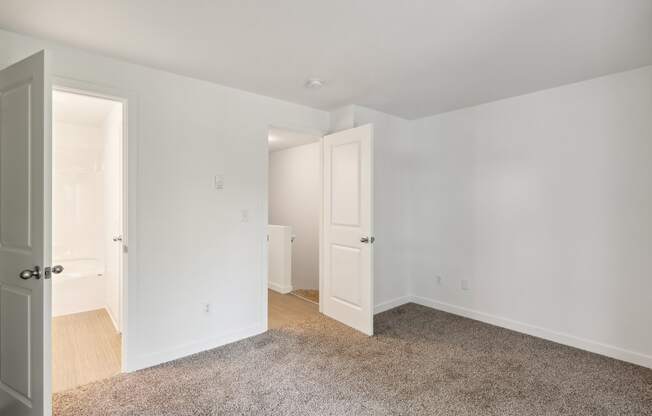 a bedroom with white walls and white doors and a carpeted floor