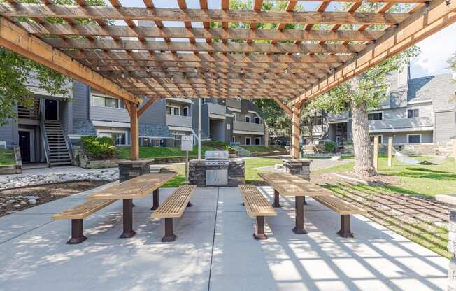 a picnic area with benches under a wooden pergola