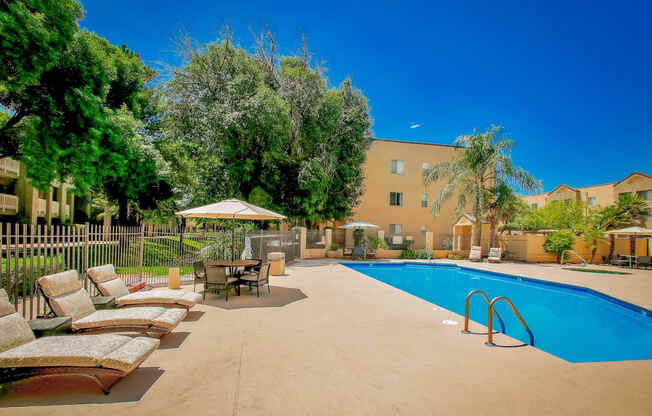 a swimming pool with lounge chairs and umbrellas next to a building