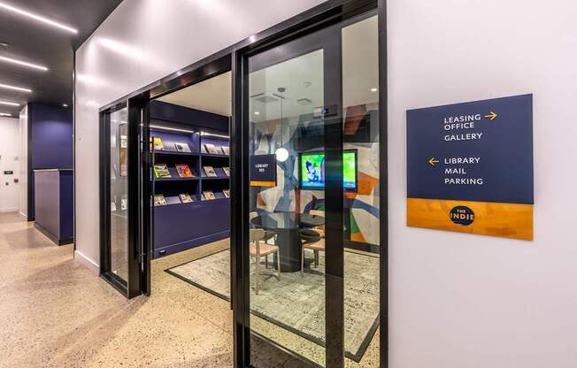 A sign in a hallway points to the leasing office, library, and parking.