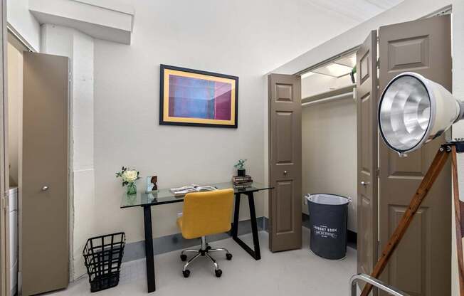 A room with a desk, chair, and a painting on the wall.