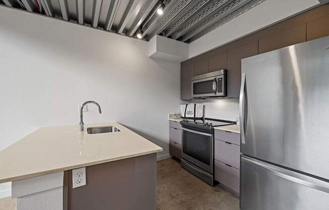 A kitchen with a stainless steel refrigerator, microwave, and oven.