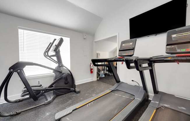 A treadmill and a stationary bike are in a room.