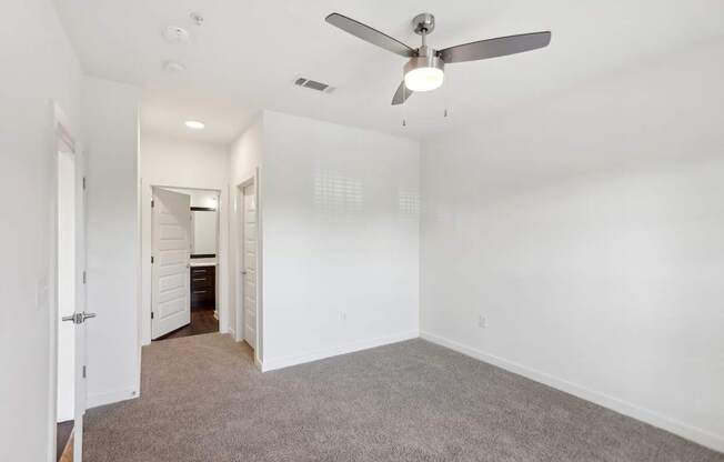 A bedroom with a ceiling fan and carpeted floor.