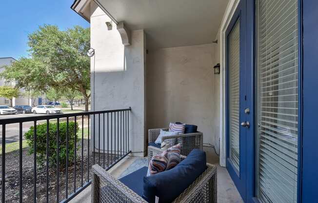 A balcony with a blue cushion and a black railing.