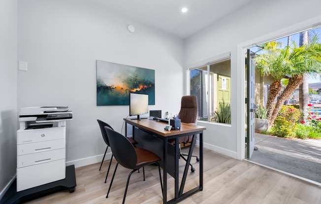 A room with a desk, chair, and a painting on the wall.