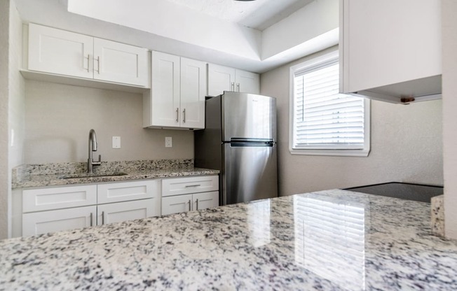 a kitchen with granite counter tops and a stainless steel refrigerator